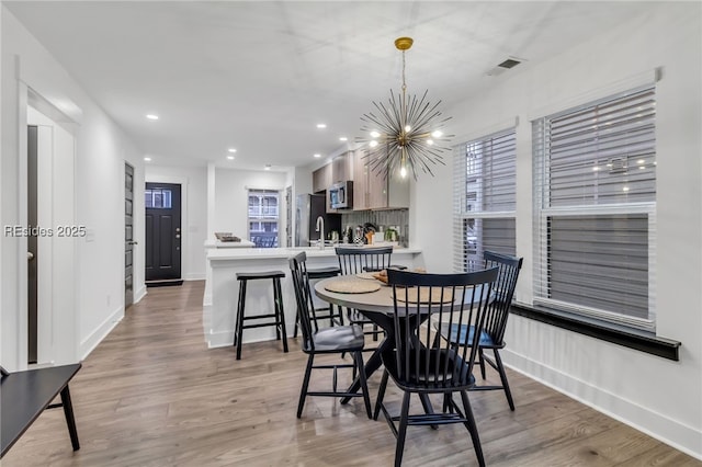 dining room with an inviting chandelier and light hardwood / wood-style flooring