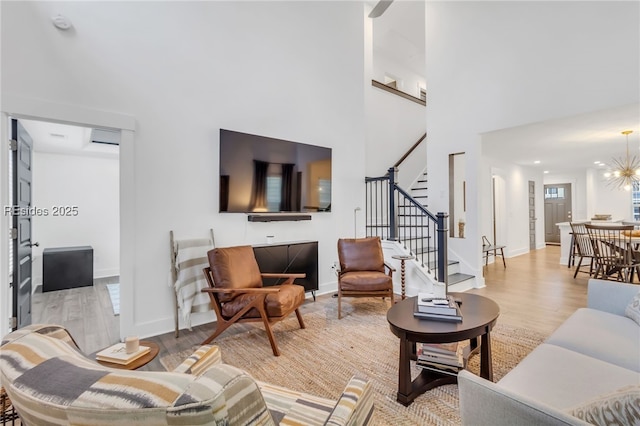 living room featuring a high ceiling, a chandelier, and light hardwood / wood-style flooring