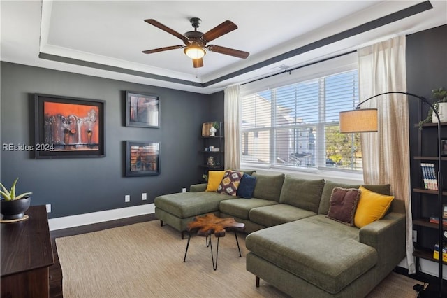 living room with hardwood / wood-style flooring, ceiling fan, and a tray ceiling