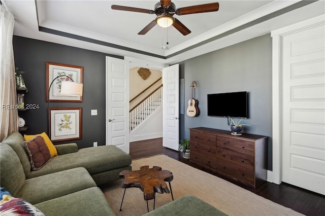 living room featuring ceiling fan, ornamental molding, a tray ceiling, and dark hardwood / wood-style flooring