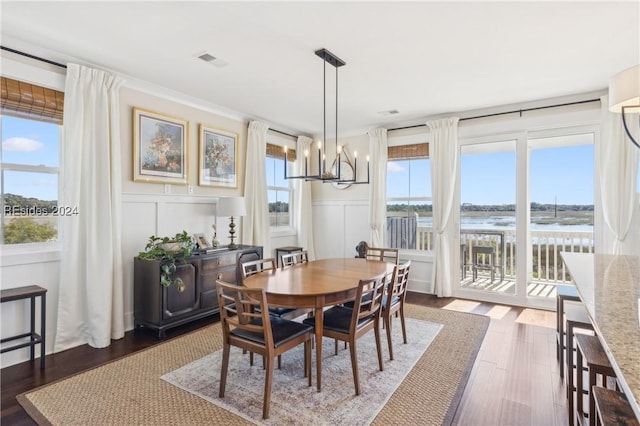 dining room featuring a water view, dark hardwood / wood-style floors, and a notable chandelier