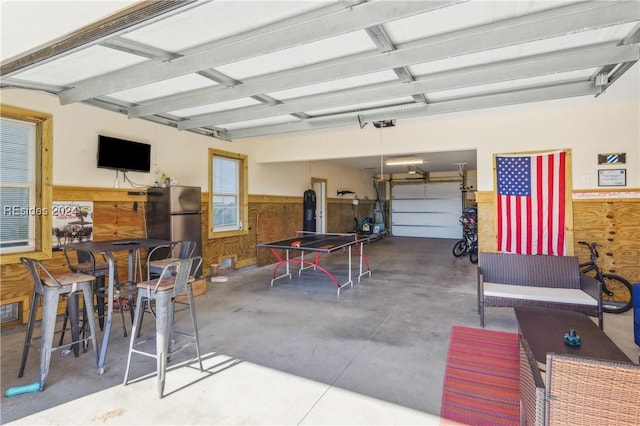 garage featuring stainless steel fridge and wooden walls