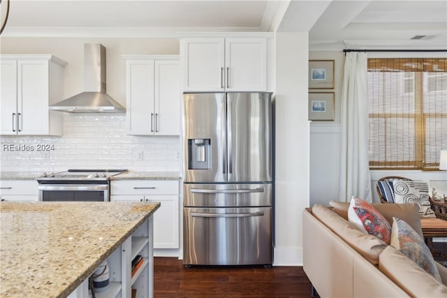 kitchen featuring white cabinetry, appliances with stainless steel finishes, light stone countertops, and wall chimney range hood