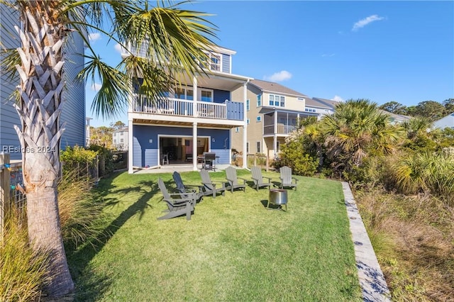 rear view of house featuring a balcony and a lawn