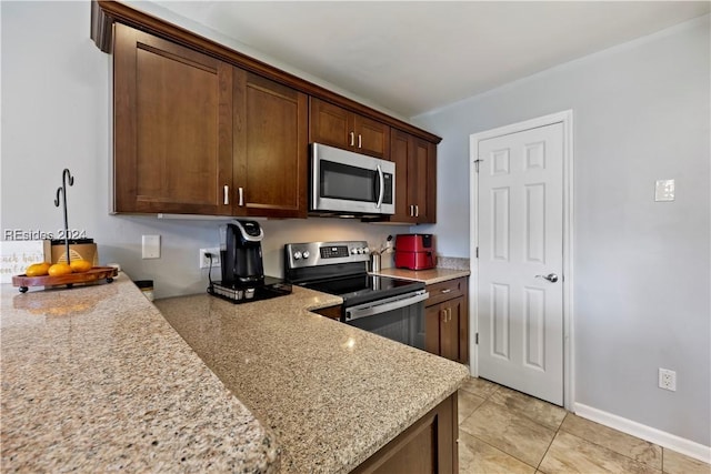 kitchen with light stone countertops, light tile patterned floors, and stainless steel appliances