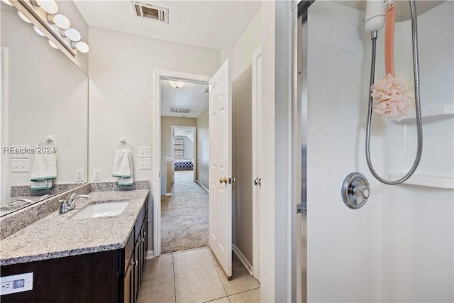 bathroom with tile patterned flooring, vanity, and walk in shower