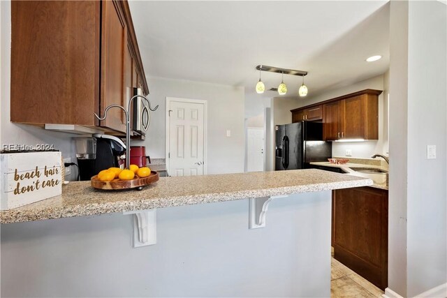 kitchen with sink, a breakfast bar area, rail lighting, black fridge, and kitchen peninsula