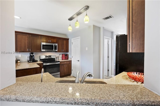 kitchen featuring sink, hanging light fixtures, dark brown cabinets, stainless steel appliances, and light stone countertops