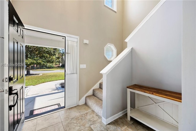 tiled entrance foyer featuring a towering ceiling