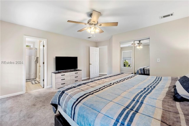 bedroom with ensuite bath, light carpet, ceiling fan, and a closet