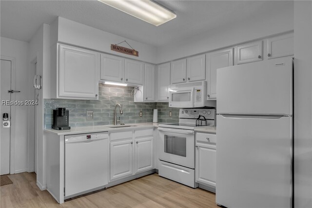 kitchen featuring tasteful backsplash, sink, light wood-type flooring, white cabinets, and white appliances