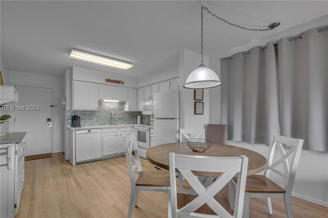 kitchen featuring hanging light fixtures, white cabinetry, backsplash, and white appliances