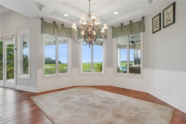 unfurnished dining area with hardwood / wood-style flooring, coffered ceiling, a chandelier, and beam ceiling