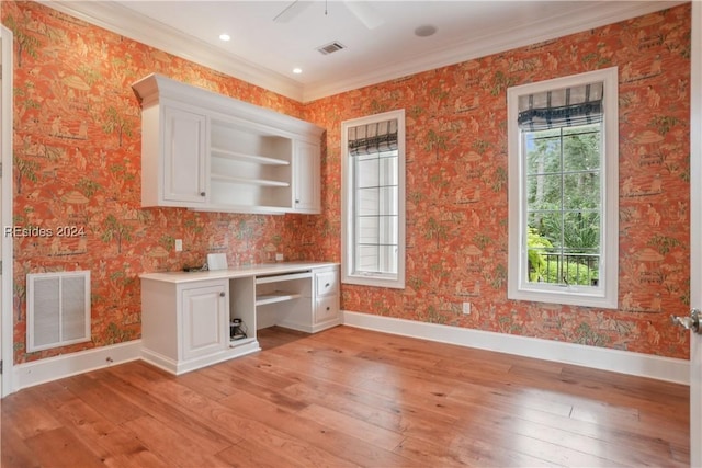 interior space with white cabinetry, ornamental molding, a healthy amount of sunlight, and light hardwood / wood-style floors