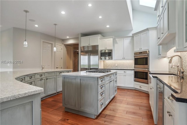 kitchen with built in appliances, decorative light fixtures, tasteful backsplash, and gray cabinetry