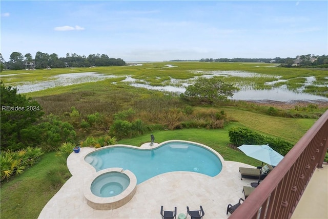 view of swimming pool with a water view, an in ground hot tub, and a lawn