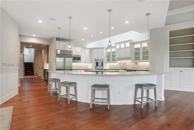 kitchen featuring built in appliances, white cabinetry, pendant lighting, and a spacious island