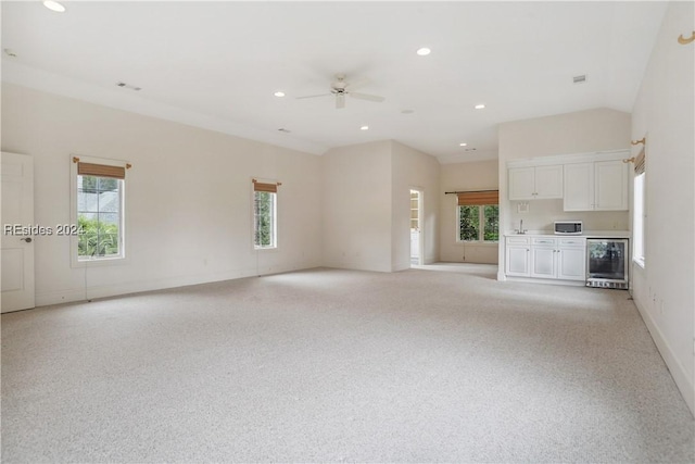 unfurnished living room with wine cooler, light carpet, and ceiling fan