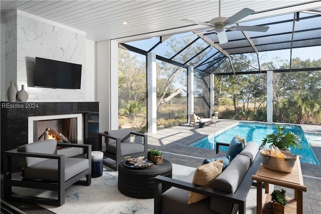 interior space featuring ceiling fan, an outdoor living space with a fireplace, and glass enclosure