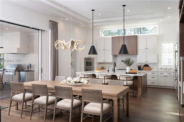 dining space featuring a raised ceiling, a healthy amount of sunlight, and dark hardwood / wood-style flooring