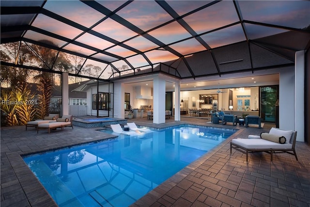 pool at dusk featuring an outdoor living space, a lanai, a patio, and an in ground hot tub