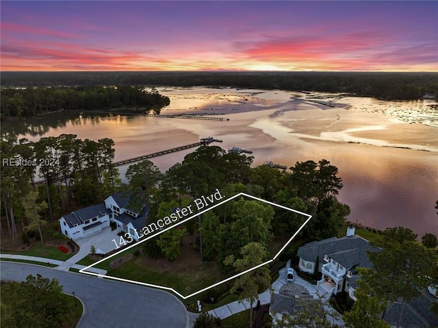 aerial view at dusk featuring a water view