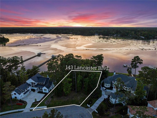 aerial view at dusk featuring a water view