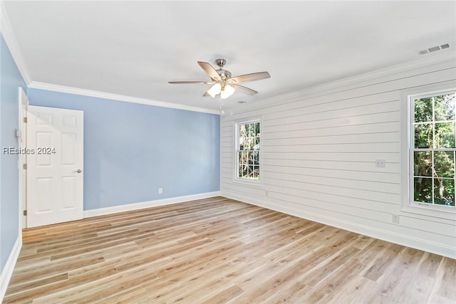 spare room with crown molding, ceiling fan, light wood-type flooring, and wood walls