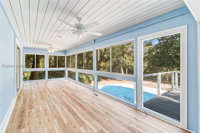 unfurnished sunroom with ceiling fan, a wealth of natural light, and wood ceiling