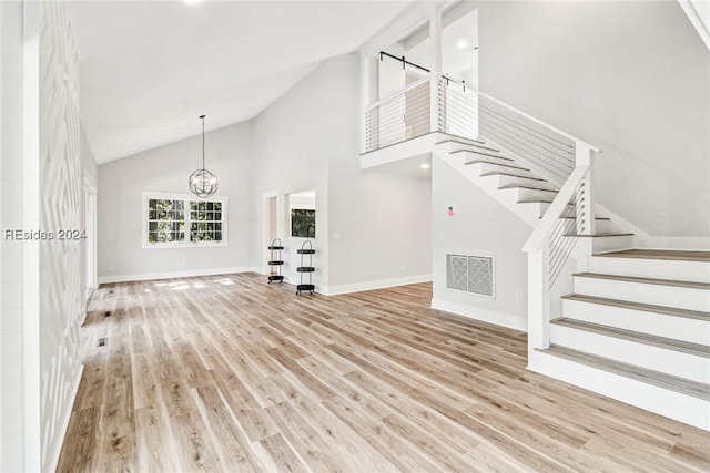 interior space with a chandelier, high vaulted ceiling, and light hardwood / wood-style flooring