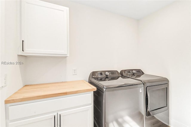 clothes washing area with cabinets, washer and dryer, and hardwood / wood-style floors