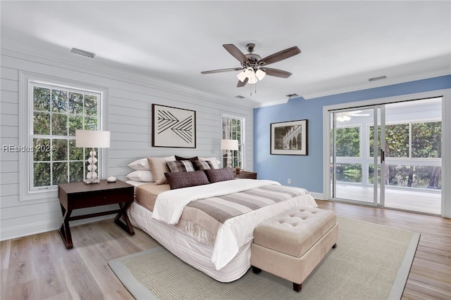 bedroom with light hardwood / wood-style flooring, access to outside, ornamental molding, wooden walls, and ceiling fan