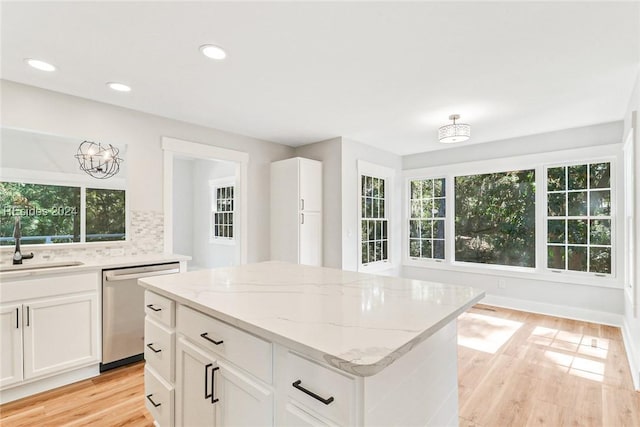 kitchen with sink, dishwasher, backsplash, a center island, and white cabinets