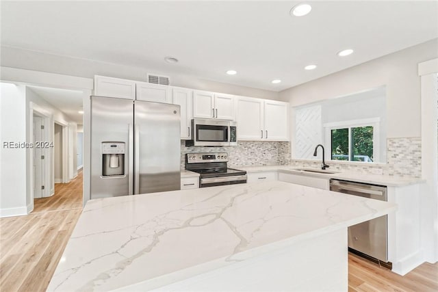 kitchen featuring appliances with stainless steel finishes, light stone countertops, sink, and white cabinets