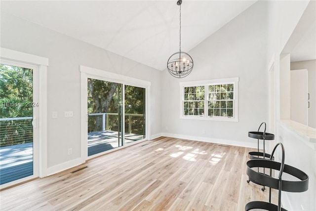 unfurnished dining area with lofted ceiling, light hardwood / wood-style flooring, and an inviting chandelier