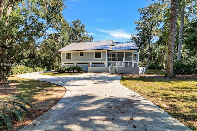 view of front facade featuring a garage, a sunroom, and a front yard