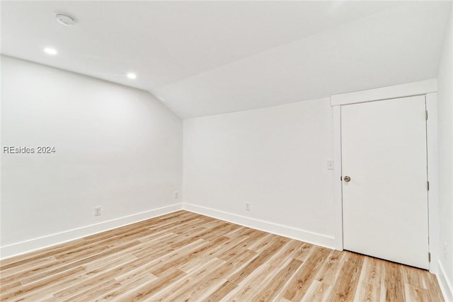 additional living space featuring vaulted ceiling and light wood-type flooring