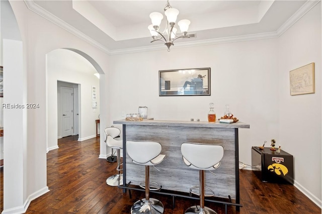 bar with dark hardwood / wood-style floors, decorative light fixtures, ornamental molding, a tray ceiling, and an inviting chandelier