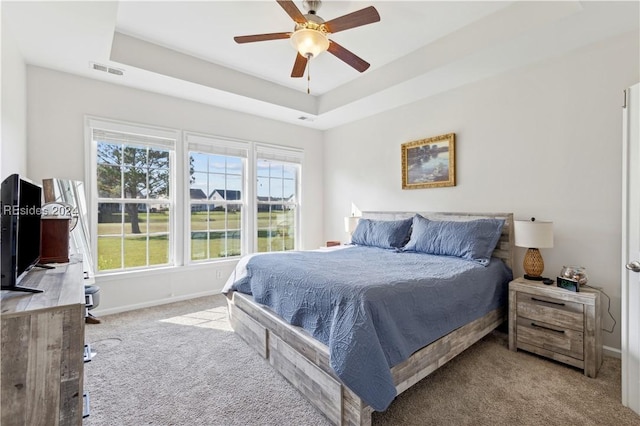 bedroom featuring ceiling fan, a raised ceiling, and multiple windows