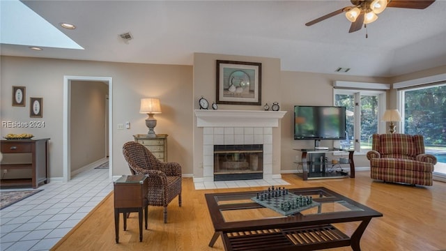 living room with vaulted ceiling, ceiling fan, hardwood / wood-style floors, and a tile fireplace