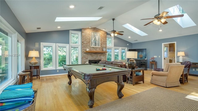 game room with billiards, lofted ceiling with skylight, light wood-type flooring, ceiling fan, and a fireplace