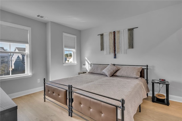 bedroom with multiple windows and light hardwood / wood-style flooring