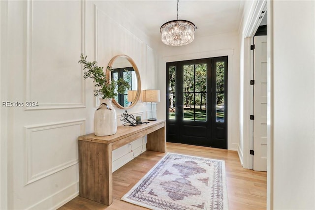 foyer entrance with an inviting chandelier, ornamental molding, and light hardwood / wood-style floors