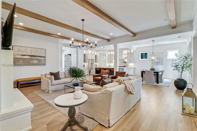 living room with an inviting chandelier, light hardwood / wood-style flooring, and beamed ceiling