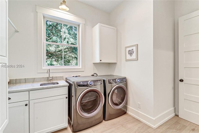 laundry area with cabinets, separate washer and dryer, sink, and light hardwood / wood-style floors