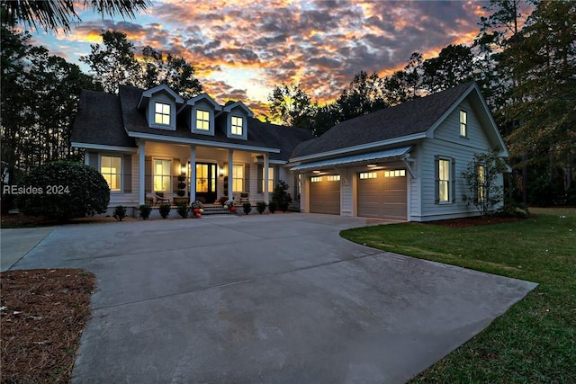 cape cod-style house with a porch, a garage, and a lawn