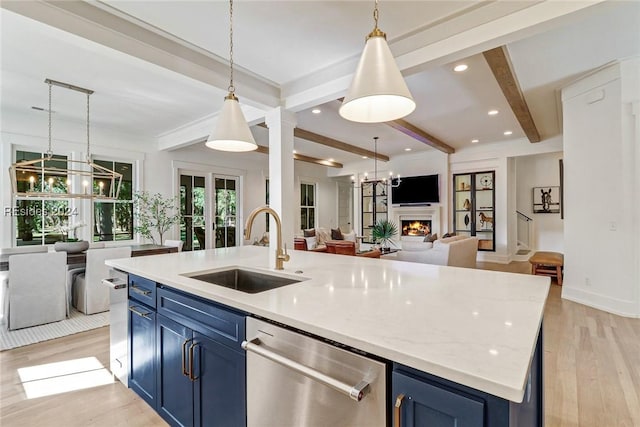 kitchen featuring pendant lighting, sink, blue cabinetry, an island with sink, and stainless steel dishwasher