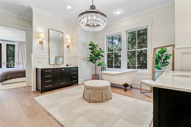 bathroom featuring crown molding, hardwood / wood-style floors, vanity, a notable chandelier, and a bathing tub