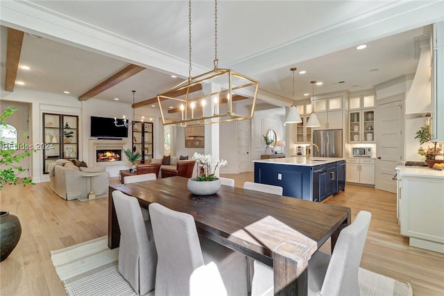 dining room with beam ceiling, sink, and light wood-type flooring