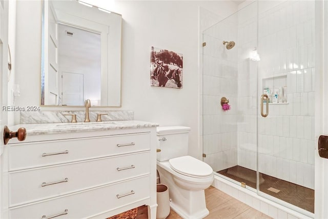 bathroom featuring hardwood / wood-style flooring, vanity, an enclosed shower, and toilet